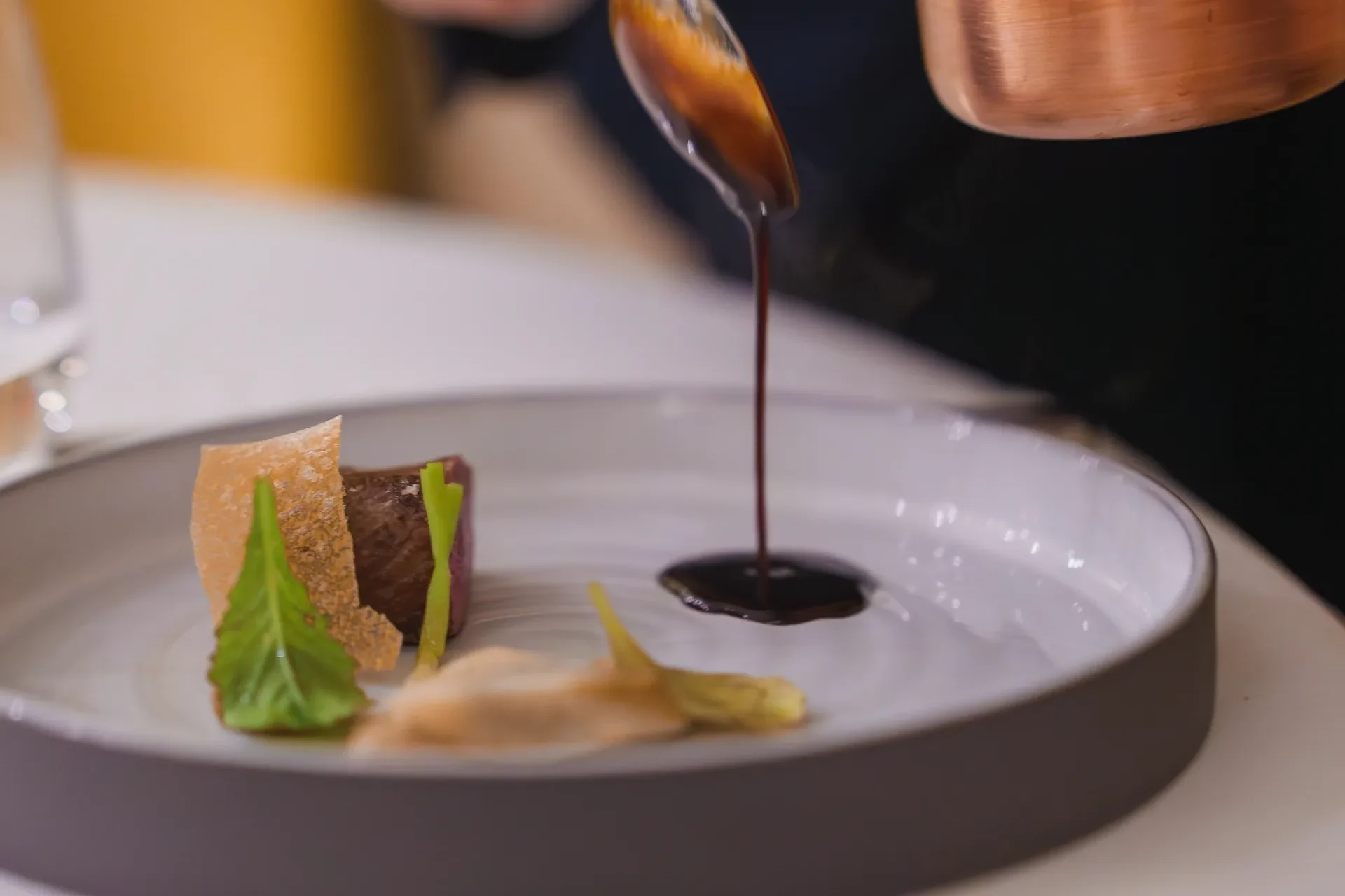 Sorgfaeltig-plattiertes-Gourmet-Gericht-mit-Fleisch-gruenen-Blaettern-und-knusprigen-Elementen